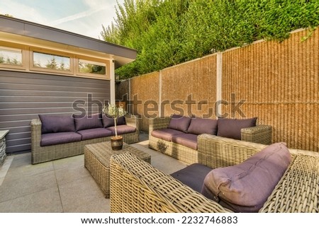 Neat powerful patio with sitting area and small garden near wooden fence