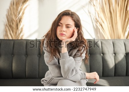 bored and sad woman sitting on couch with no mood and prop up head with hand Royalty-Free Stock Photo #2232747949