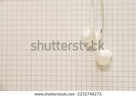 white earphones on a grid background mobile phone, copy space