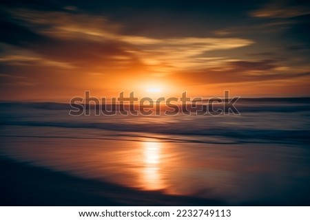 Abstract seascape. Red sunset, motion blur. Tranquil scene of empty sand beach at sunset
