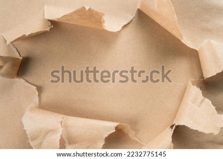 Beige crumpled packaging paper unwrapping from center, ragged paper. Unpacking and bursting from the center. Presents for holidays. Sustainable resource, eco friendly. Overlay, copy space, top view Royalty-Free Stock Photo #2232775145