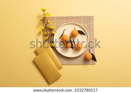 Lunar New Year with mandarin orange, bamboo blind, yellow apricot flower, and lucky envelopes on yellow background.  AsiaTraditional Holiday. Royalty-Free Stock Photo #2232780517