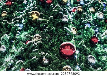Christmas balls and glowing garlands on an artificial spruce. Xmas abstract background.
