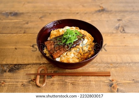 bowl of eel and rice topped with boiled eggs