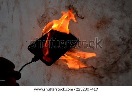 Cell phone battery failure. A smartphone can quickly catch fire and set fire to a house, apartment, or car. there is a risk of burns to the device user. flames surround entire tablet, laptop, computer Royalty-Free Stock Photo #2232807419
