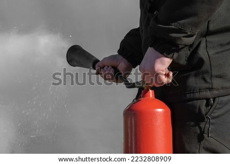 A man is holding a carbon dioxide fire extinguisher in his hands. The concept of working with a fire extinguisher. Background picture.