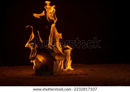 A toy house in a ring of fire. Background picture. Space for printing text. Soft focus.