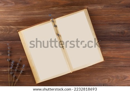 Education learning concept with opening book or textbook. Open book with lavender flowers on wooden table, education, learning, study, culture. Top view, copy space.