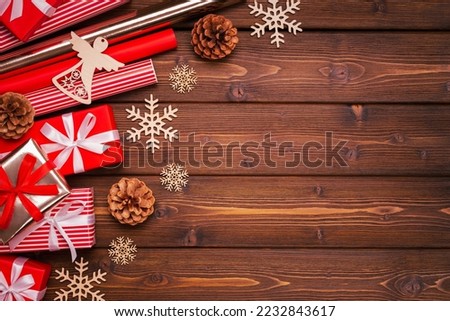 Winter holiday background with red gifts, white bows, snowflakes, cones and an angel on brown boards. Layout, basis. Gift wrapping, handmade,creativity, hobbies.