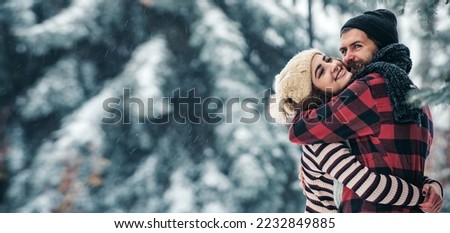 Young couple hug in snow winter background. Couple in love embrace on Christmas background outdoor. Young couple in love on snow scene banner.