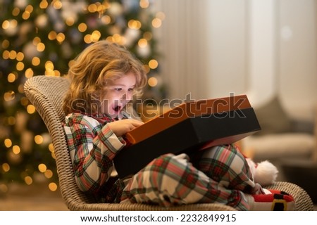 Surprise kid opening Christmas present gift box. Child preparing for the Christmas and New Year holidays.