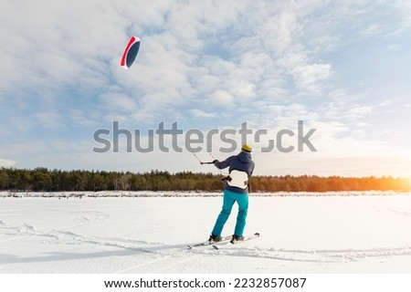 Panoramic view of many people friends enjoy riding kite surf board in warm suit on bright sunny winter day at frozen lake field snowy surface. Wintersport adrenaline fun adventure hobby acitivity Royalty-Free Stock Photo #2232857087