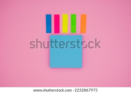 Bookmarks and blue blank sticky notes on pink background. Copy space for text
