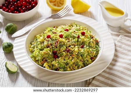 brussels sprouts slaw with almonds, crunchy fried bacon and cranberries in white bowl on wooden table with olive oil lemon dressing, landscape view from above Royalty-Free Stock Photo #2232869297