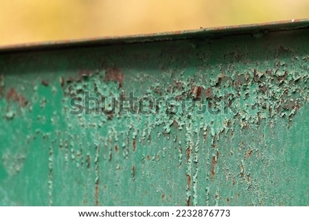 Green weathered metal rusty fence close-up with blurry background. Territory border protection