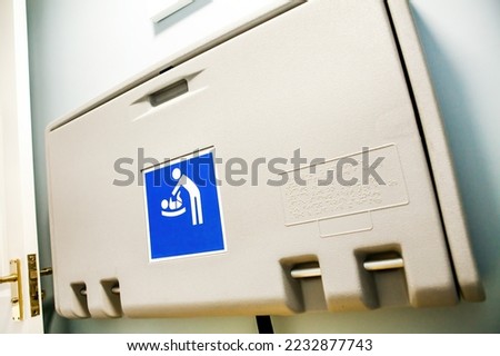 Baby nappy diaper changing table in a public toilet restroom. Child changing board in a toilet.  Blue sign