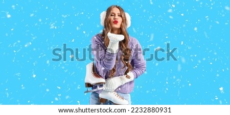 Beautiful young woman with ice skates blowing kiss on light blue background