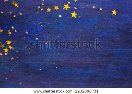 Dark-blue wooden board with golden stars  and  empty space for text. Top view.