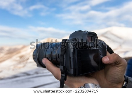 A man takes a photo in the snowy mountains
