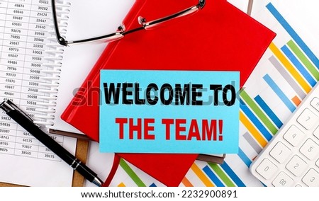 WELCOME TO THE TEAM text on a sticky on red notebook on chart background