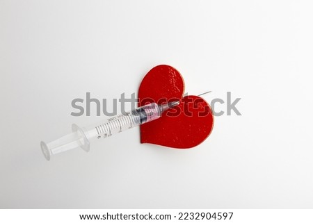 a heart pierced with a medical syringe with a needle