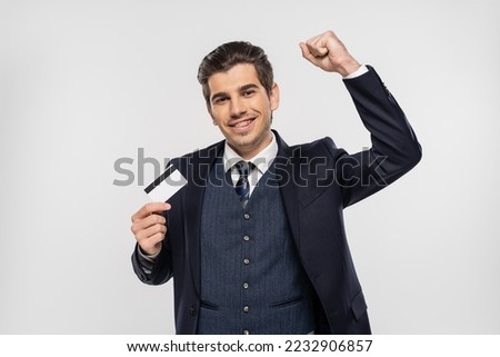 happy businessman with braces holding credit card and looking at camera isolated on grey