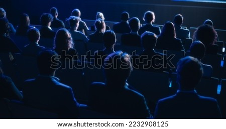 Audience Full of Tech People in Dark Conference Hall Watching an Innovative Inspiring Keynote Presentation. Business Technology Summit Auditorium Room Crowded with Delegates. Static Shot from Behind. Royalty-Free Stock Photo #2232908125