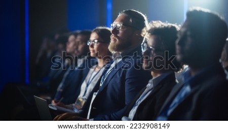 Stylish Caucasian Man Sitting in a Crowded Audience at a Political Rally. Corporate Delegate Taking Notes in a Laptop. Government Employee Attending Ministry Policy Makers Conference. Royalty-Free Stock Photo #2232908149