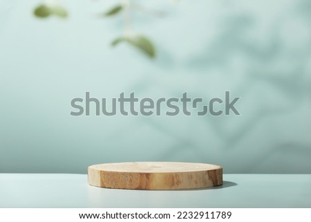 Abstract empty Wood slice podium with eucalyptus leaves and shadows on blue background. Mock up stand for product presentation. 3D Render. Minimal concept. Advertising template Royalty-Free Stock Photo #2232911789