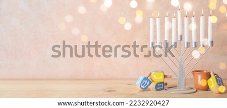 Menorah with candles, jug and dreidels for Hanukkah celebration on wooden table. Banner for design