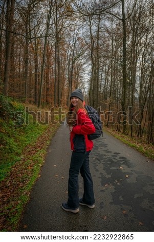 young tourist woman with backpack in an autumnal forest. A single independent courageous and happy woman.