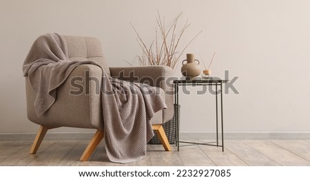 Interior of modern living room with soft armchair, table and plaid Royalty-Free Stock Photo #2232927085