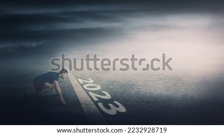 Determined man stands ready in running position at the starting line, looking ahead confident. Guy sprinter begins the new 2023 year challenges. Competitive winner behaviour and motivation concept Royalty-Free Stock Photo #2232928719