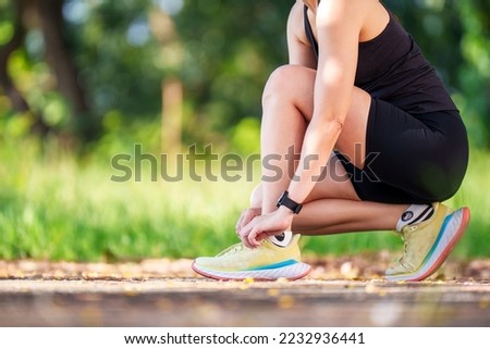 Woman runner checking choes in order to get ready to run.runner tighting running shoes before run for exercise in the evening.  Royalty-Free Stock Photo #2232936441