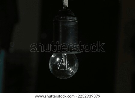 Electric light bulb on a black background. The light bulb does not glow because there is no electricity. Concept of blackouts in Ukraine. Royalty-Free Stock Photo #2232939379