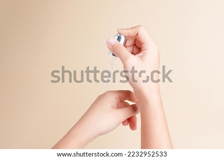 Beautiful female hands dropping skin care or serum isolated on pastel yellow background with copyspace Royalty-Free Stock Photo #2232952533