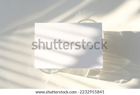 Blank business card mockup on glass with shade of natural leaves shadow overlay on white background, for product or presentation 