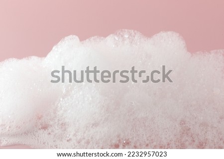 Fluffy bath foam on pink background, closeup Royalty-Free Stock Photo #2232957023