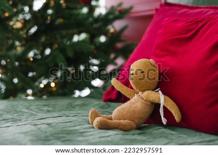 Vintage toy bear on the bed near the pillows on the background of Christmas lights