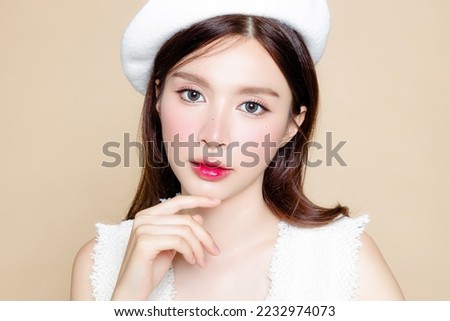 Cute Asian woman with perfect clear fresh skin. Pretty girl model wearing white beret and natural makeup on beige background. Cosmetology, beauty and spa, wellness, Plastic surgery. Royalty-Free Stock Photo #2232974073