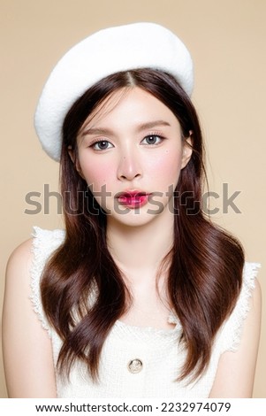 Cute Asian woman with perfect clear fresh skin. Pretty girl model wearing white beret and natural makeup on beige background. Cosmetology, beauty and spa, wellness, Plastic surgery. Royalty-Free Stock Photo #2232974079