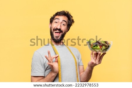 young crazy bearded man dieting happy expression and holding a salad