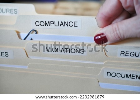 A female hand removing a Compliance folder from a cabinet full of files and folders in office at work Royalty-Free Stock Photo #2232981879