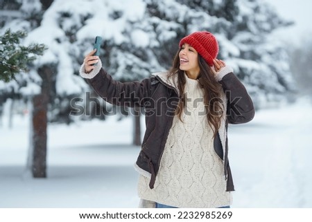 Young woman taking selfie in winter forest. Holidays, rest, travel concept.