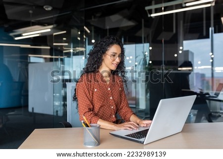 Cheerful and successful indian woman programmer at work inside modern office, tech support worker with laptop typing on keyboard smiling. Royalty-Free Stock Photo #2232989139
