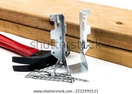 A galvanized steel joist hanger with hammer and nails as be used n residential construction Royalty-Free Stock Photo #2232990121