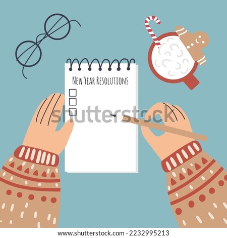 Unidentified person writes New Year resolutions. Female, male, gender neutral hands in sweater hold pencil and notepad. Hot winter drink and glasses. Royalty-Free Stock Photo #2232995213