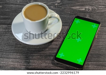 phone with a green tap and a cup of coffee on a wooden surface, breakfast, snack, order by phone