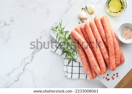 Meat beef sausages. Raw barbecue sausages with spices, vegetables and ingredients for cooking on white background. Top view. Copy space. Oktoberfest menu concept.