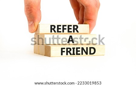 Refer a friend symbol. Concept words Refer a friend on wooden blocks on a beautiful white table white background. Businessman hand. Business and refer a friend concept. Copy space.